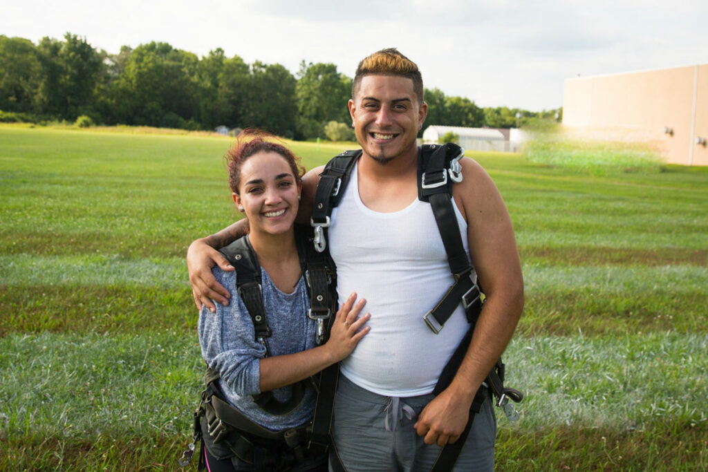 Skydiving couple smiling together after landing.